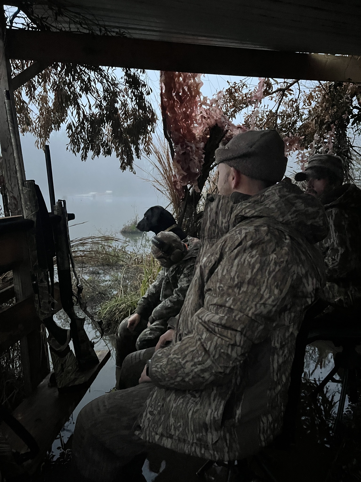 Hunter in duck blind watching over foggy water